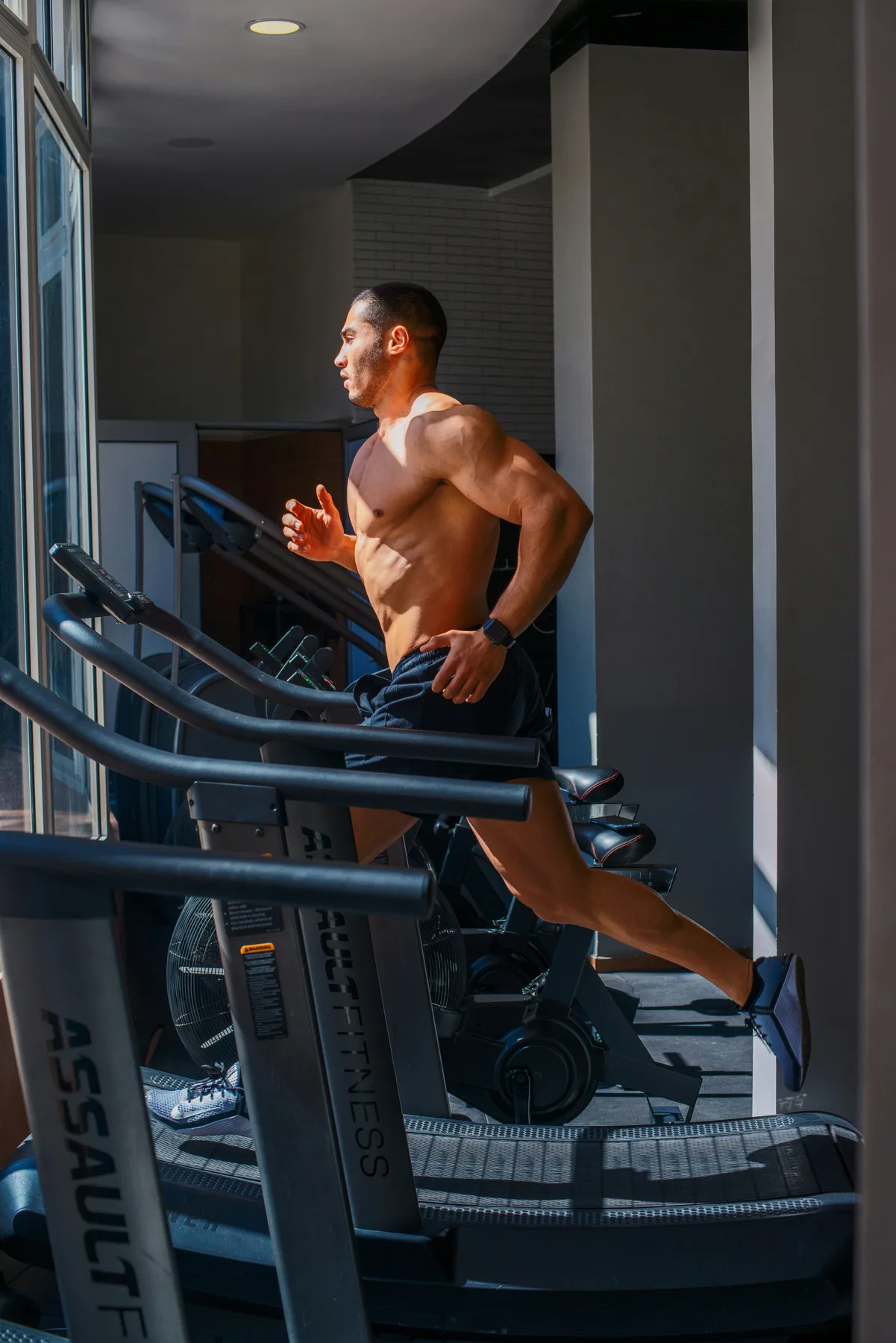 A person running on a treadmill by a window in a training room