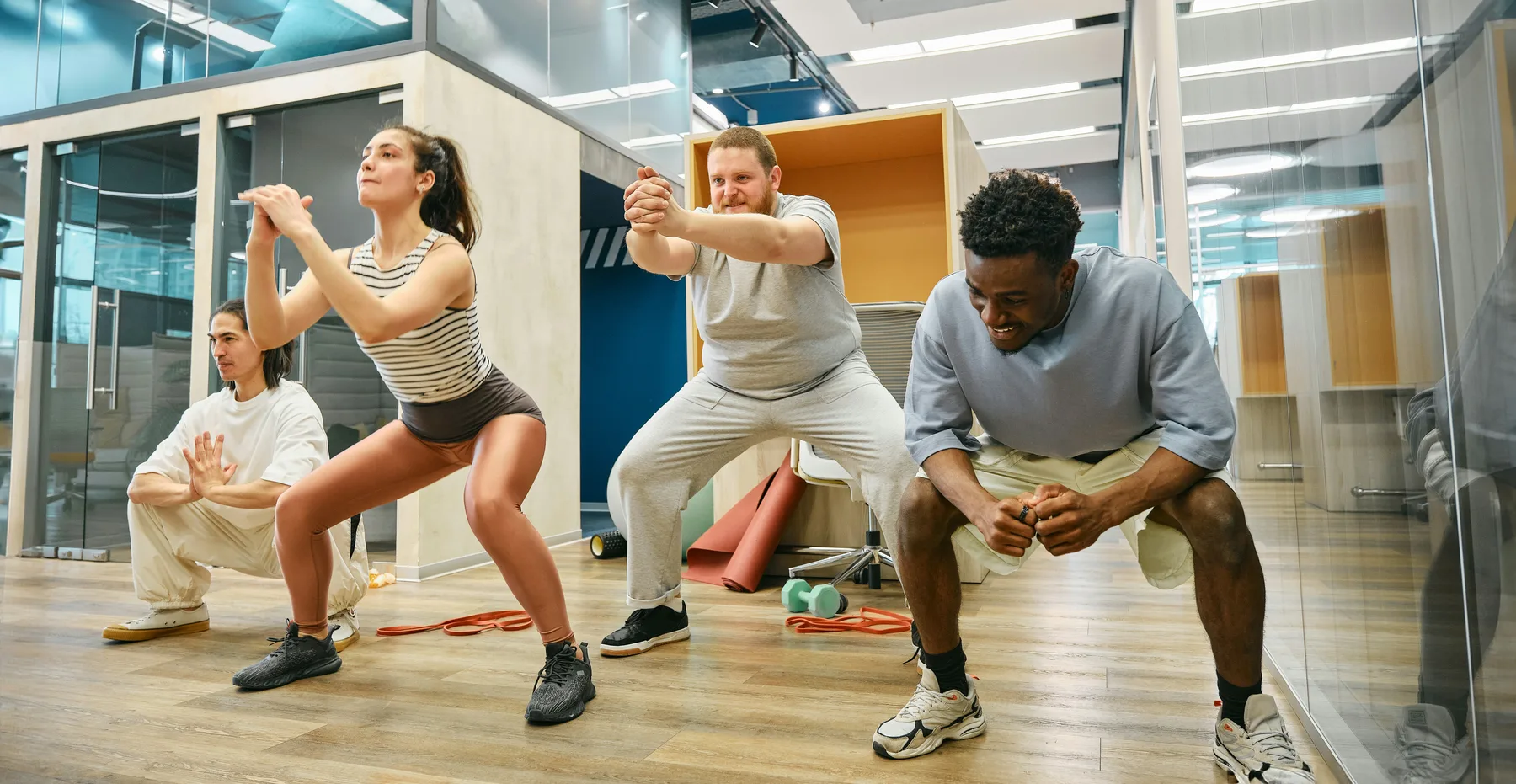 Employés faisant des squats ensemble dans un espace d'entraînement au bureau