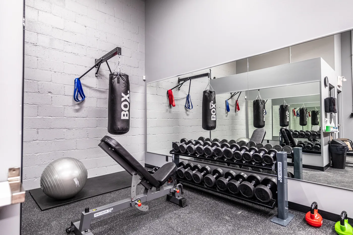Zone d’entraînement avec banc, haltères et sacs de boxe chez Gicleurs F.F.